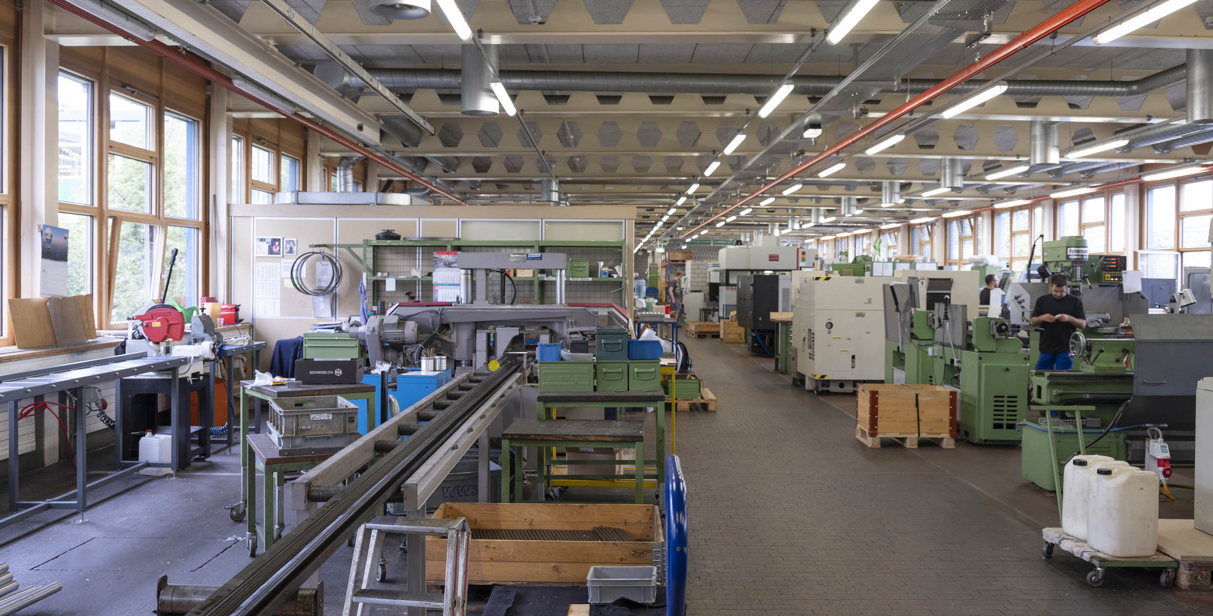 Die Werkstatt der Mechanik: Ein grosser Raum mit vielen Maschinen und einigen Mitarbeitenden