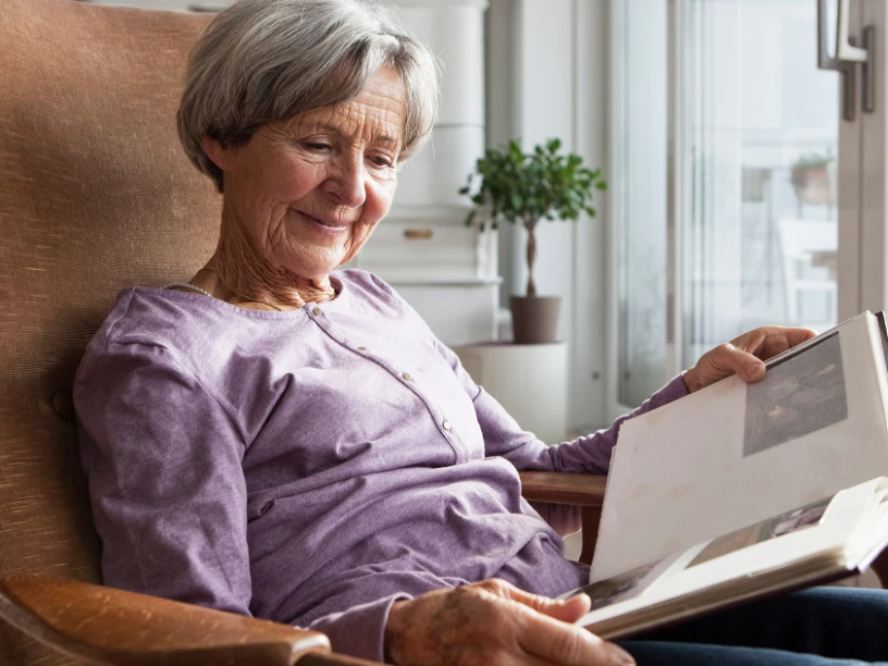 Seniorin im Sessel schaut sich ein Fotoalbum an