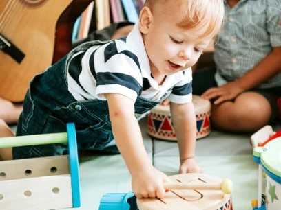Ein kleines Kind, das mit einer hölzernen Trommel spielt