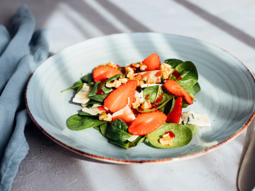 Ein Salatteller mit Erdbeeren, Spinat, Käse und Walnüssen